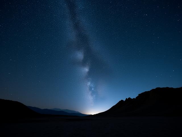 Cielo estrellado impresionante sobre un paisaje desértico, vía láctea visible.